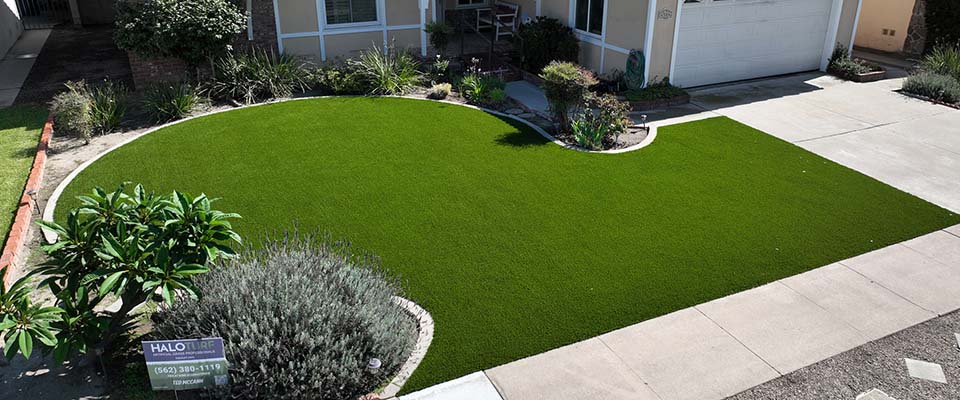 Front yard with an artificial turf lawn and low-water plants around it